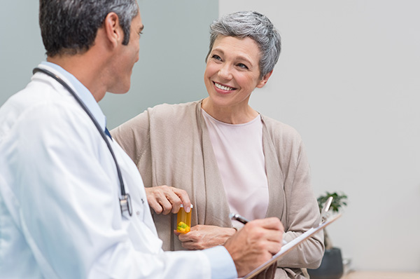 A smiling middle-aged woman talking with a male doctor.